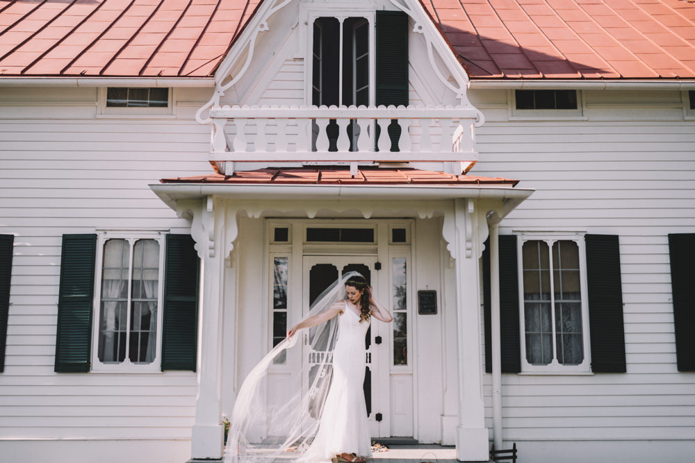 bride fixing her veil in front of a farmhouse in columbus ohio