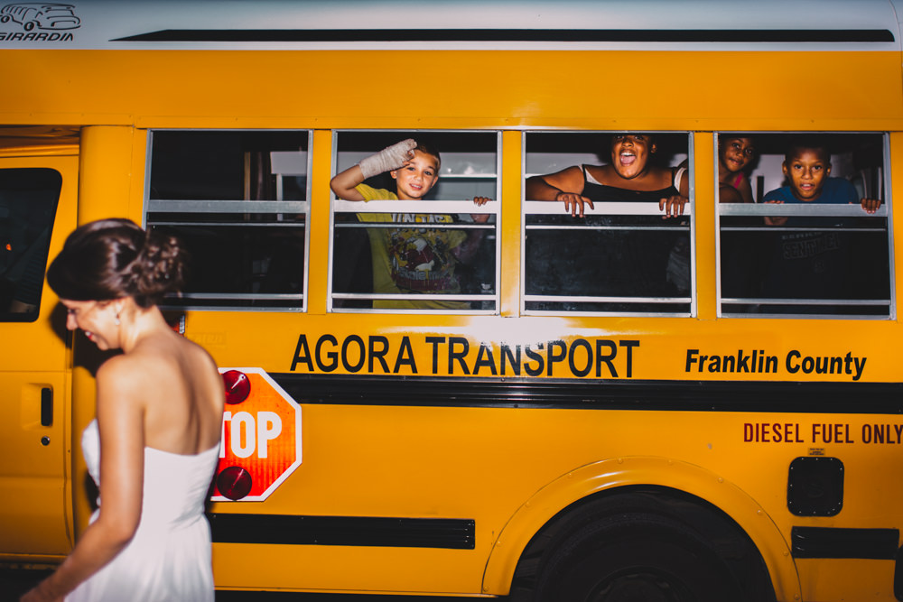 kids in a school bus waving at a columbus bride and groom