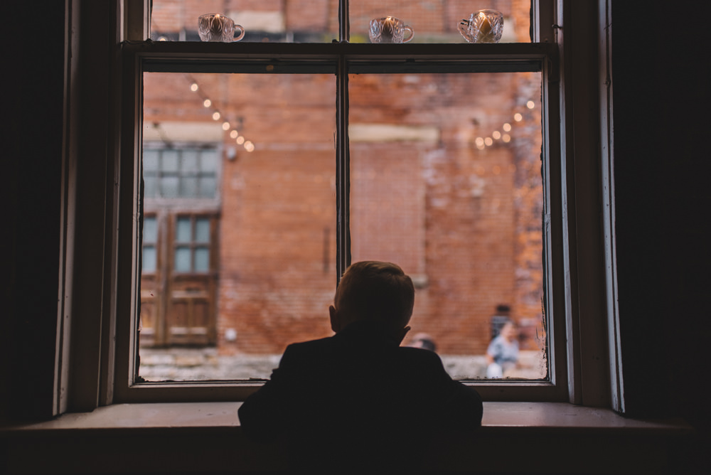 ring bearer looking out of a window at a via vecchia winery wedding photography