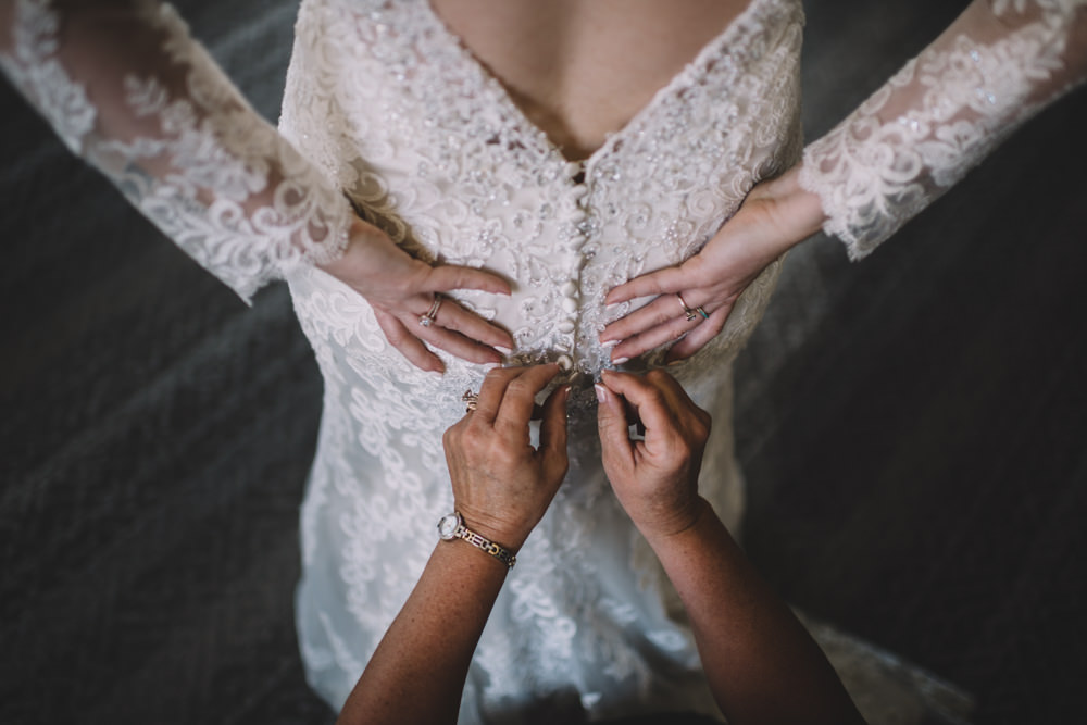 bride's mom helping put her dress on